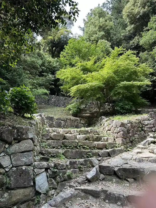 Stone steps and walls near the residence ruins attributed to Takei Sekian, rising up a tree-covered slope.