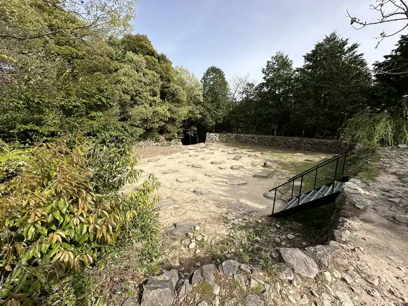 A full view of the top of the Azuchi Castle Tenshudai. Natural stones and pillar bases are scattered across the foundation, with a viewing staircase in place.