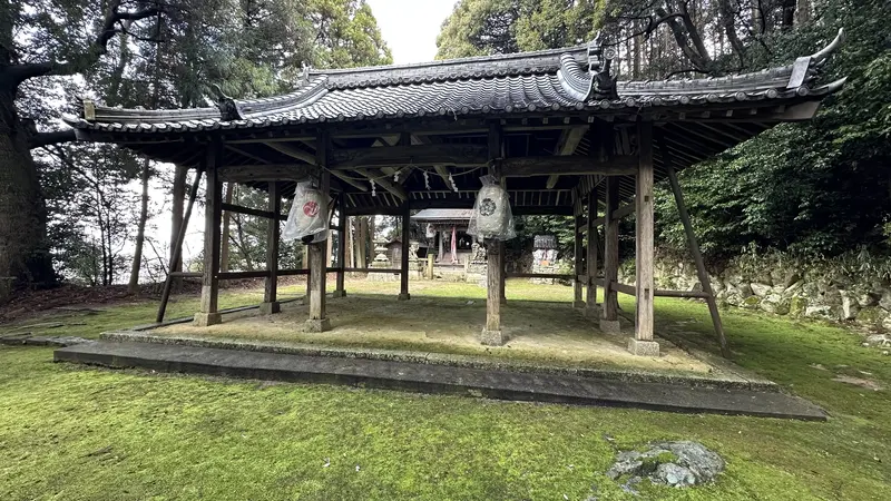 A roofed worship hall at Ishibe Shrine near Dodobashiguchi, with lanterns hanging over a moss-covered shrine ground.