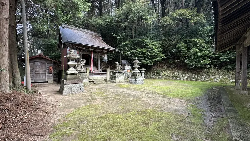 The main sanctuary of Ishibe Shrine near Dodobashiguchi, standing beyond a row of stone lanterns.