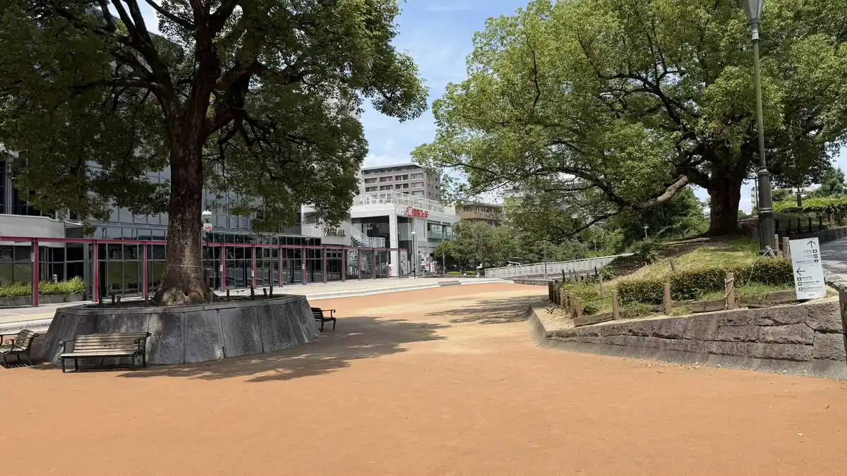 Open lawn with a large tree and restored features at Arioka Castle Ruins Historical Park