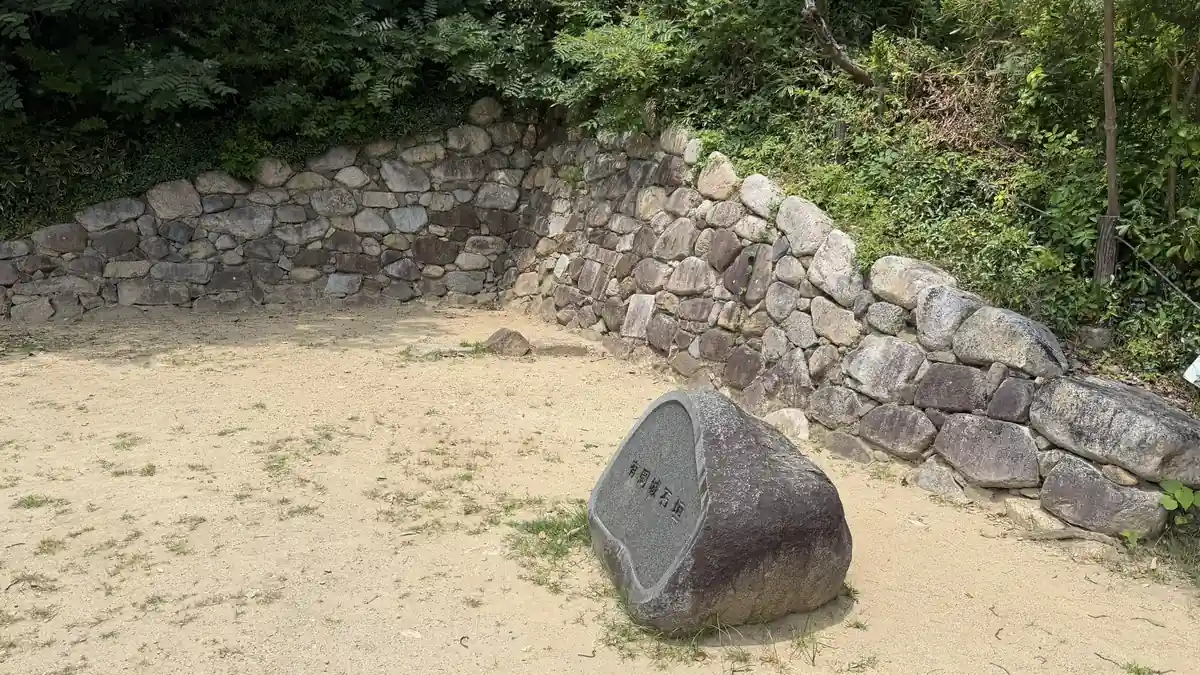 Marker stone for building foundations beside a stone wall at Arioka Castle
