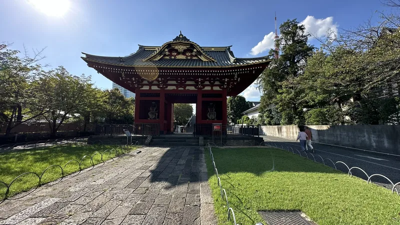 Red former main gate of the Taitoku-in Mausoleum with Tokyo Tower behind it
