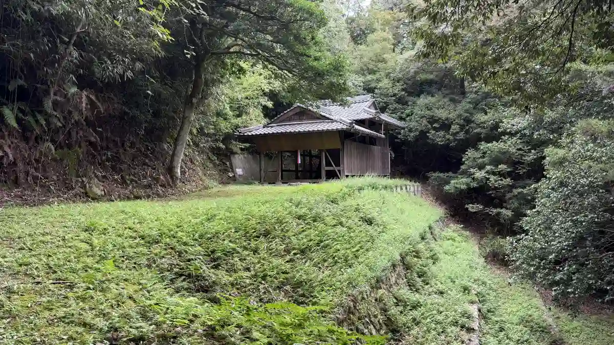 緑の斜面の先、木々に囲まれた場所に木造の小さな社殿が姿を現します。