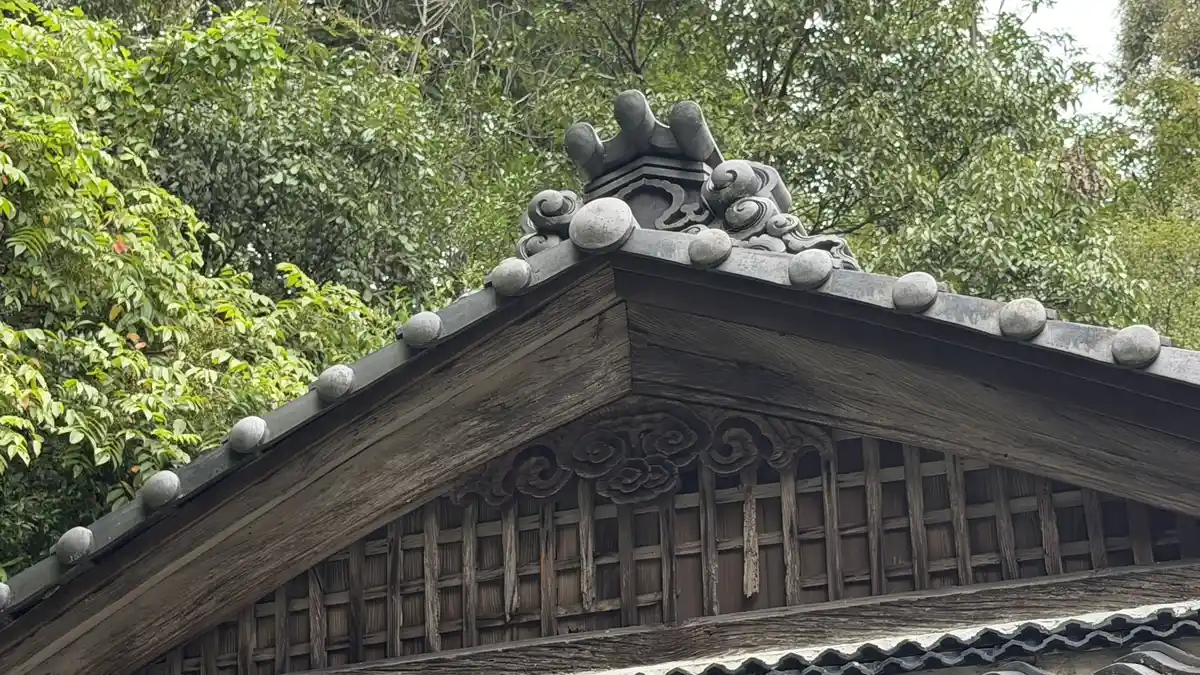 木造覆屋の屋根を見上げた写真。瓦葺きの棟と端部の鬼瓦が見えます。