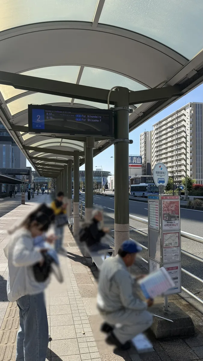 The covered bus stop at the south exit of Higashi-Shizuoka Station, with a passenger reading the timetable for services towards Nihondaira (image edited to obscure the person)