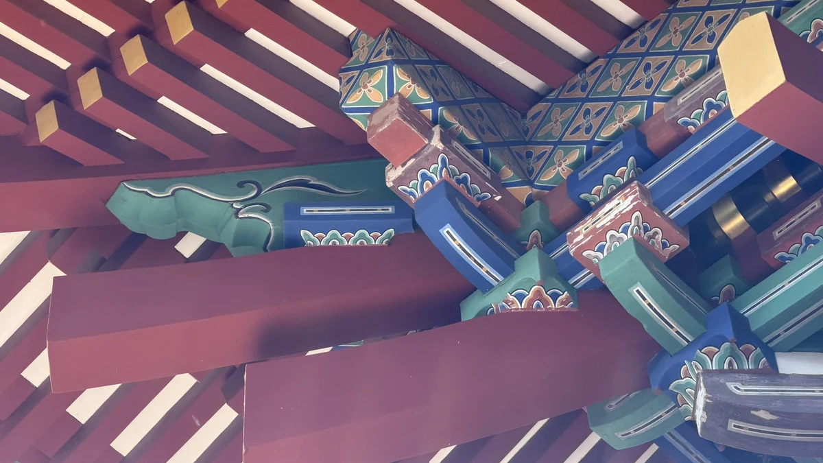 Looking up under the eaves of the Romon gate at vermilion beams and blue and green bracket clusters
