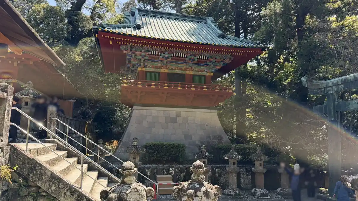 The vermilion drum tower on its stone base above a flight of steps and stone lanterns (image edited to obscure a person)