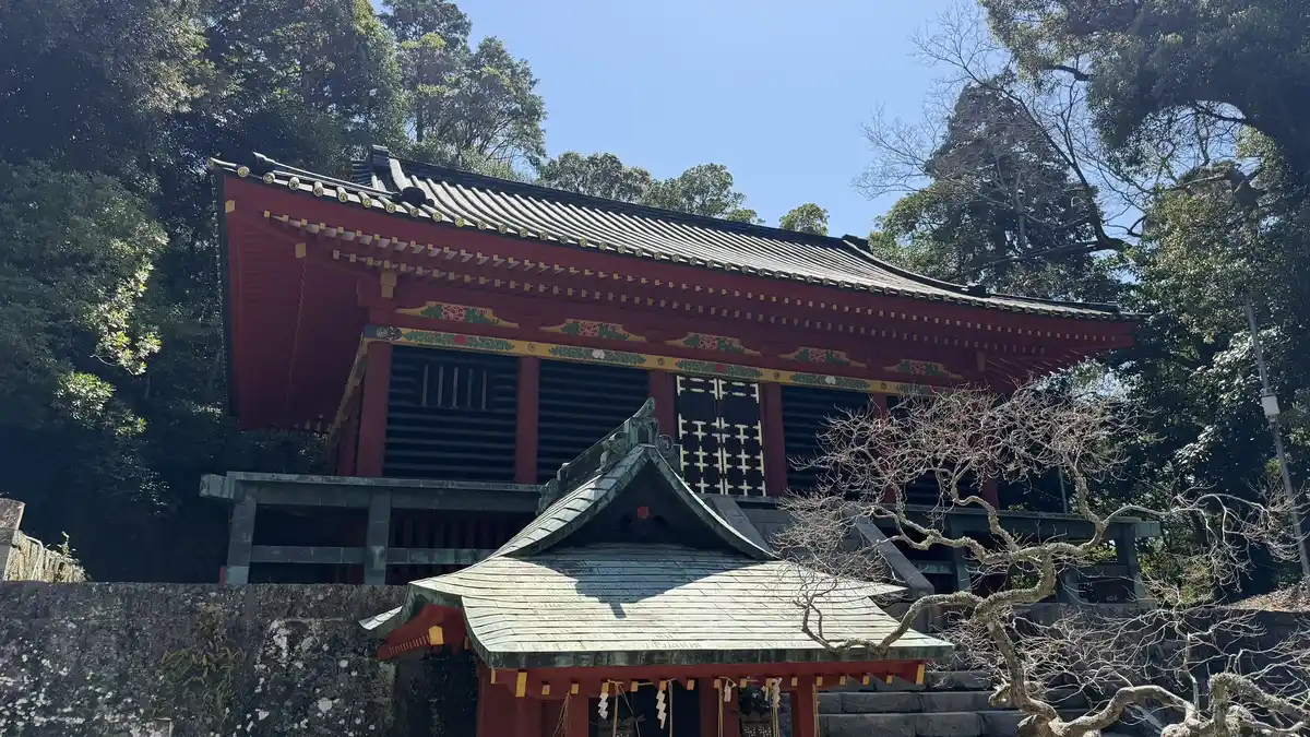 The Hie Shrine with vermilion walls and a long roof, seen through trees in the precinct of Kunozan Toshogu