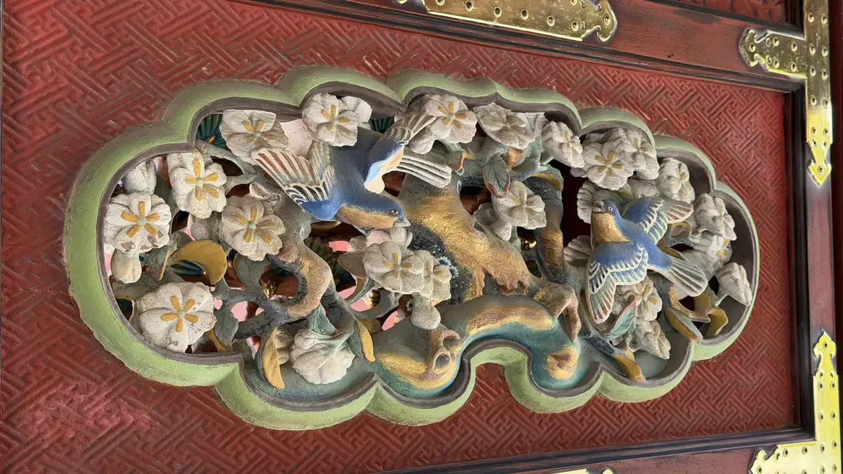 Multicoloured openwork carving of flowers and animals on a panel of the shrine buildings