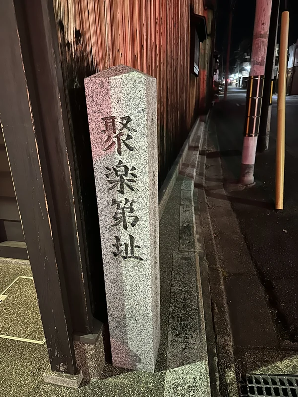 町家の板壁ぎわに立つ「聚楽第址」と刻まれた石標
