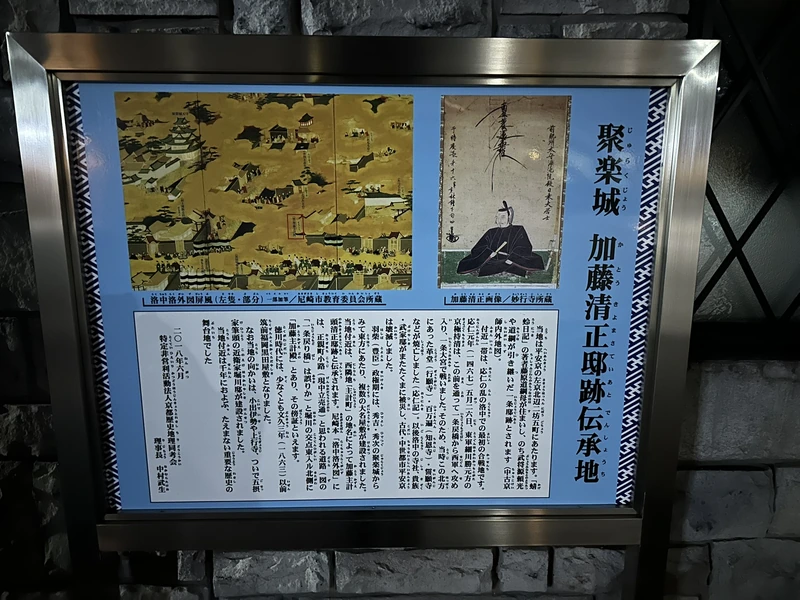 聚楽城加藤清正邸跡伝承地の青い解説パネル。屏風の図版と肖像が載る
