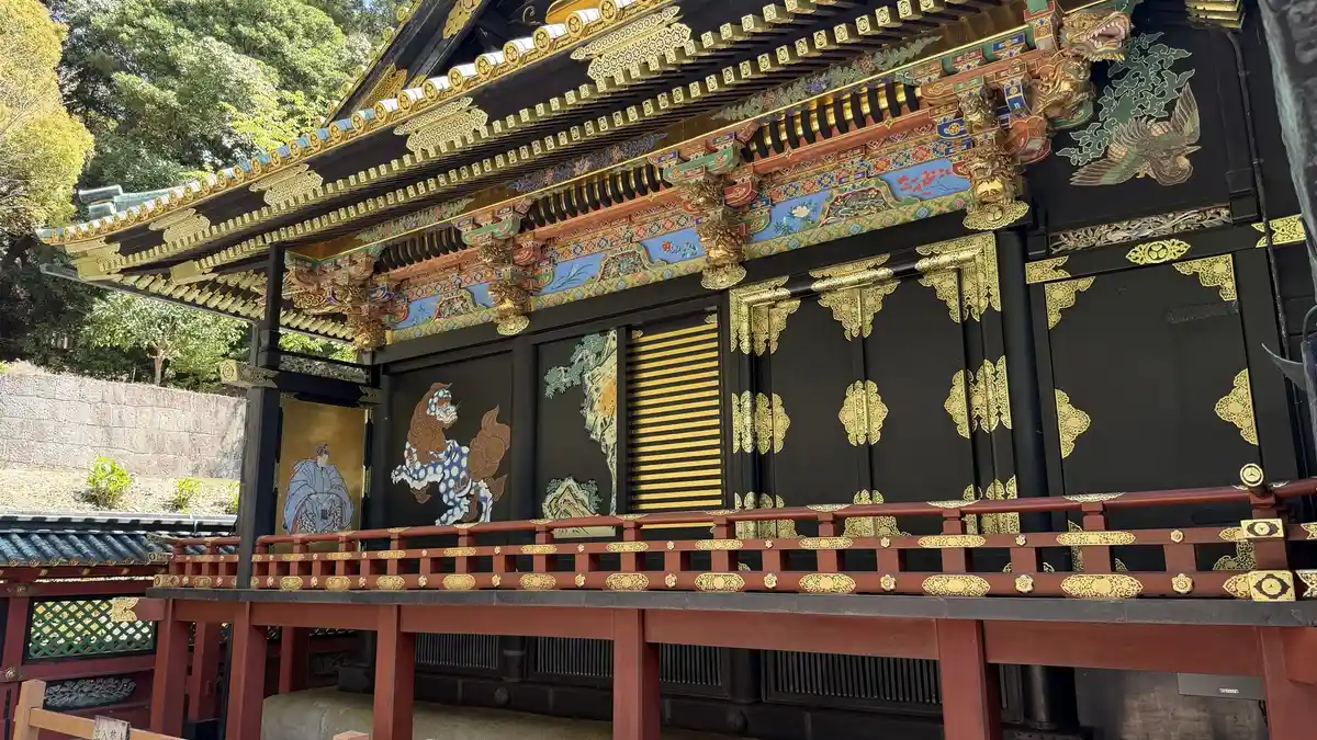 The National Treasure main shrine buildings of Kunozan Toshogu seen at an angle, with painted carvings under the eaves and vermilion railings