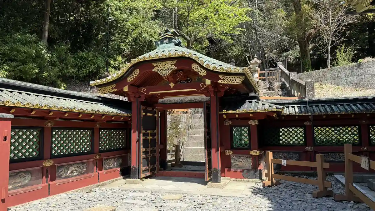 A small gate with a curved gable set into the vermilion fence around the shrine buildings