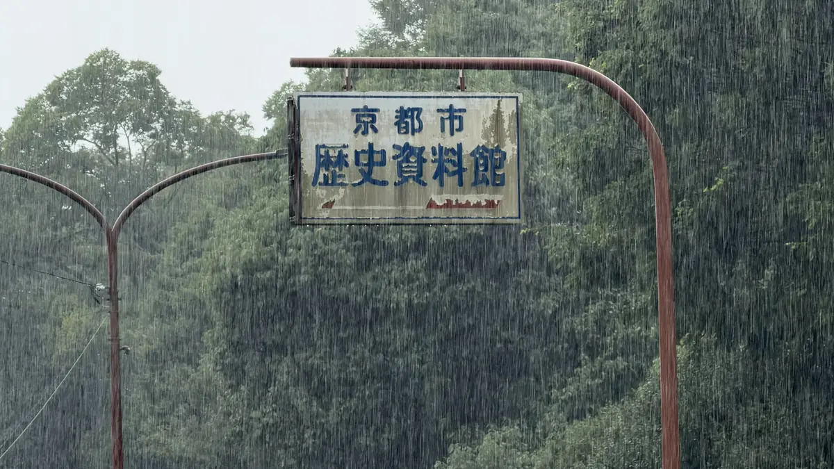 激しい雨の中、街路灯に掲げられた京都市歴史資料館の館名看板