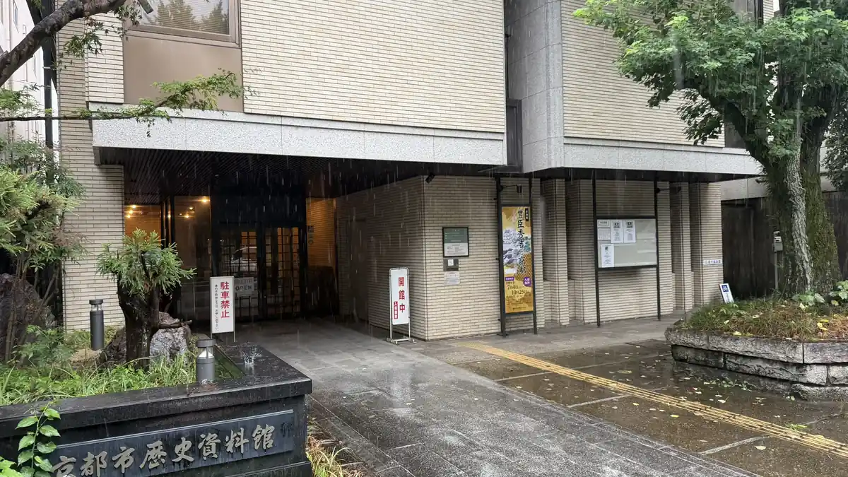 雨の中の京都市歴史資料館入口と企画展『豊臣秀吉と京都』の縦長看板