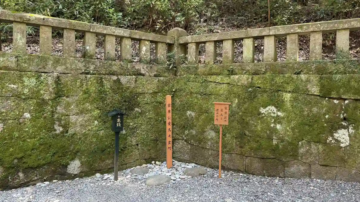 A moss-covered stone wall and fence with a caution sign around Ieyasu's mausoleum at Kunozan Toshogu