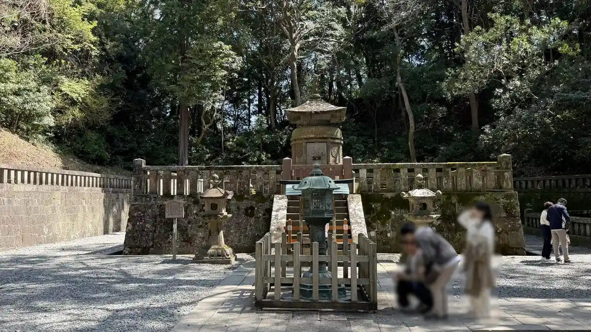 The stone pagoda of the mausoleum seen past a stone lantern in the foreground (image edited to obscure a person)