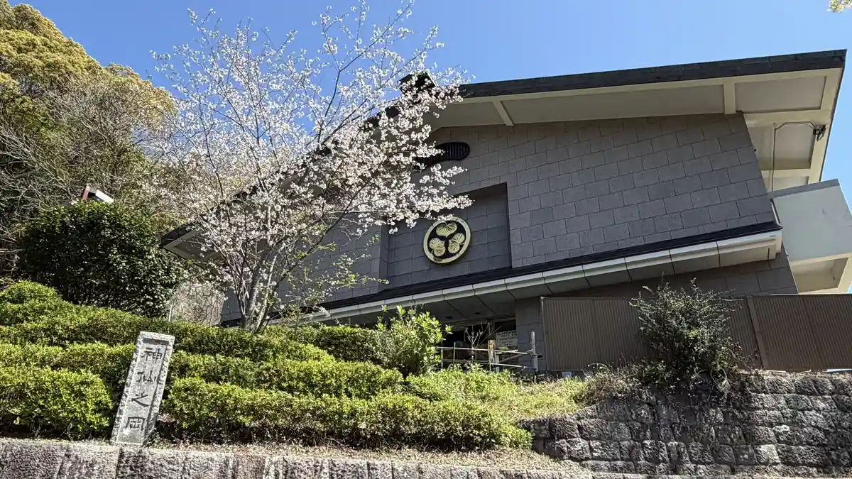 The Kunozan Toshogu Museum building carrying a large Tokugawa hollyhock crest, with greenery and cherry blossom in front