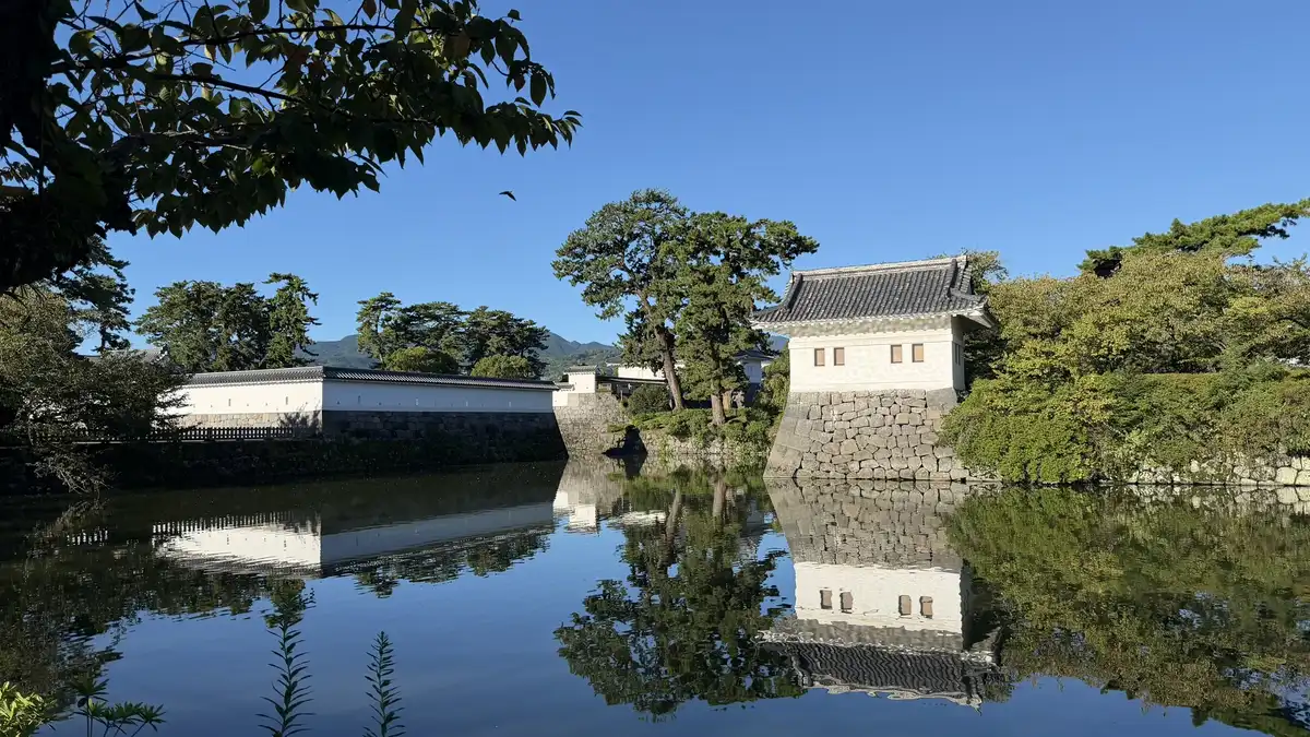 Ninomaru corner turret and adjoining wall seen across the moat, with hills beyond