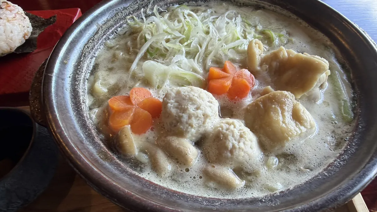 Milky chicken broth with chicken dumplings and vegetables in a clay pot
