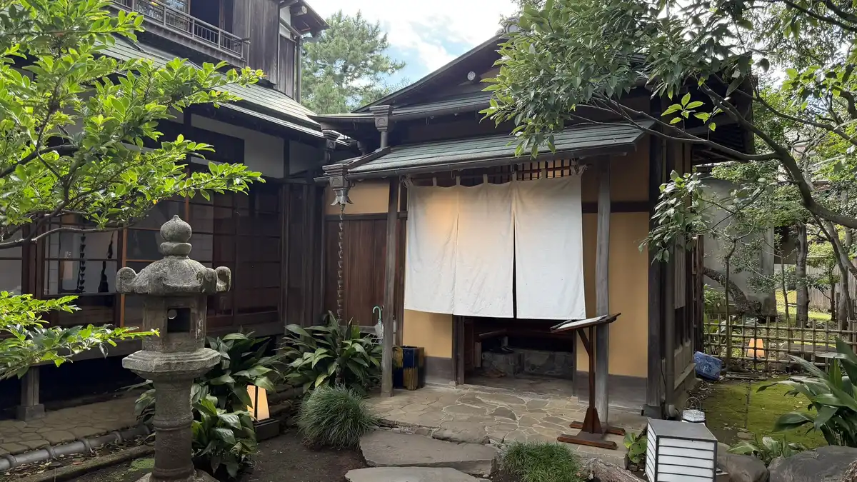 Entrance of Seikantei with a white noren curtain and stone lanterns
