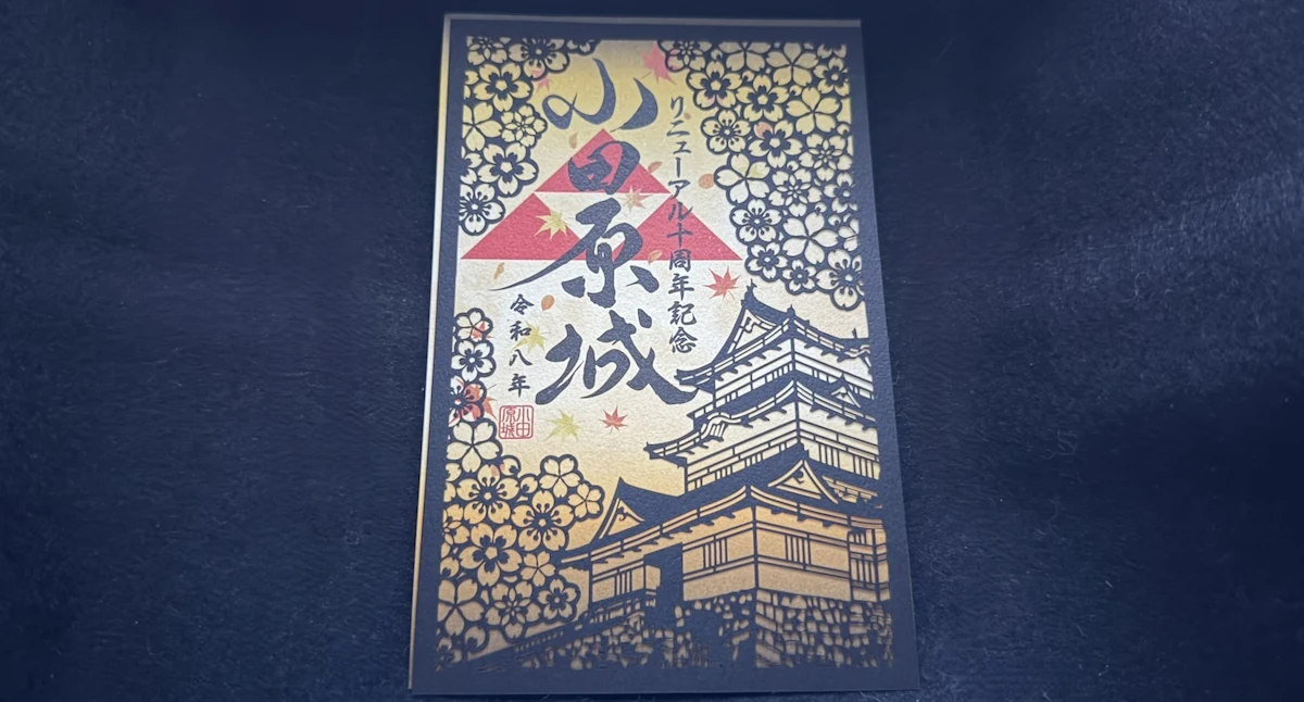 Paper-cut Odawara Castle goshuin showing the keep among cherry blossoms and autumn leaves