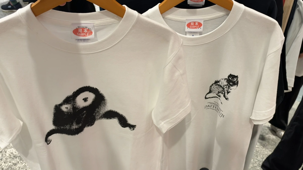 White sample T-shirts printed with a pair of gibbons and a tiger at the exhibition shop