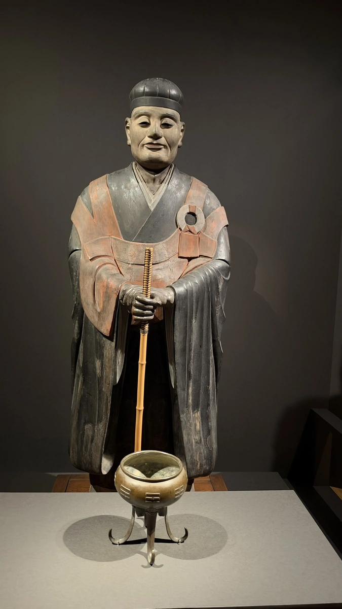 A vertical frontal view of Sen no Rikyu’s statue, showing his face, robes, hands and staff