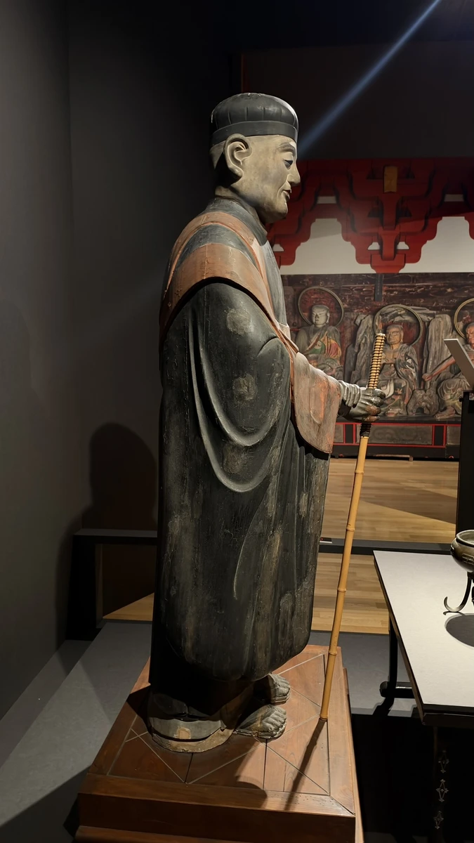 A full side view of Sen no Rikyu’s statue, including the cap, long robes, staff and footwear