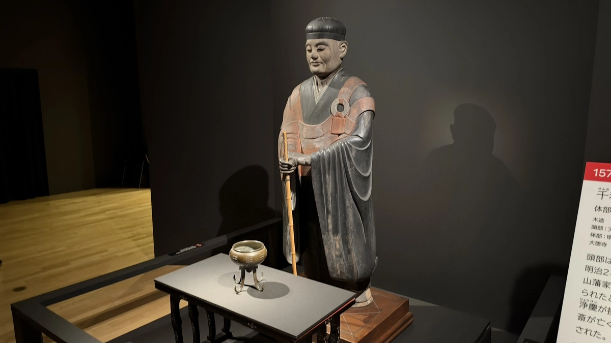 Sen no Rikyu’s statue with an incense burner in front and part of its label at the right edge