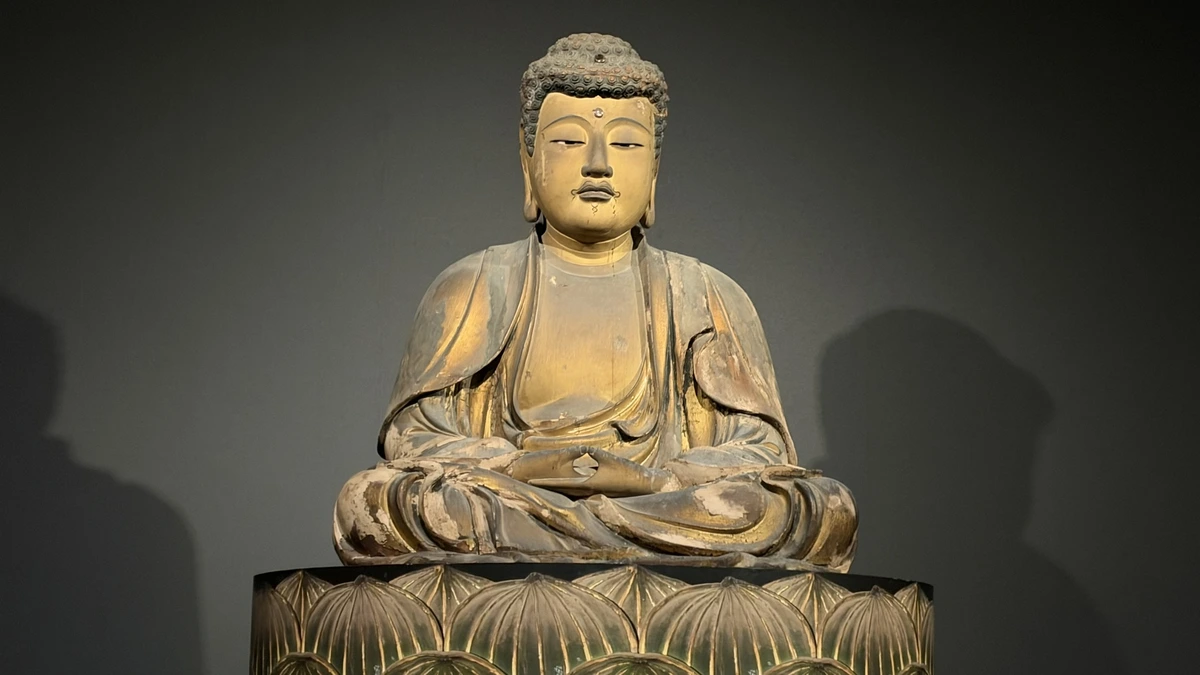A close frontal view of the seated Shakyamuni with hands resting together in his lap