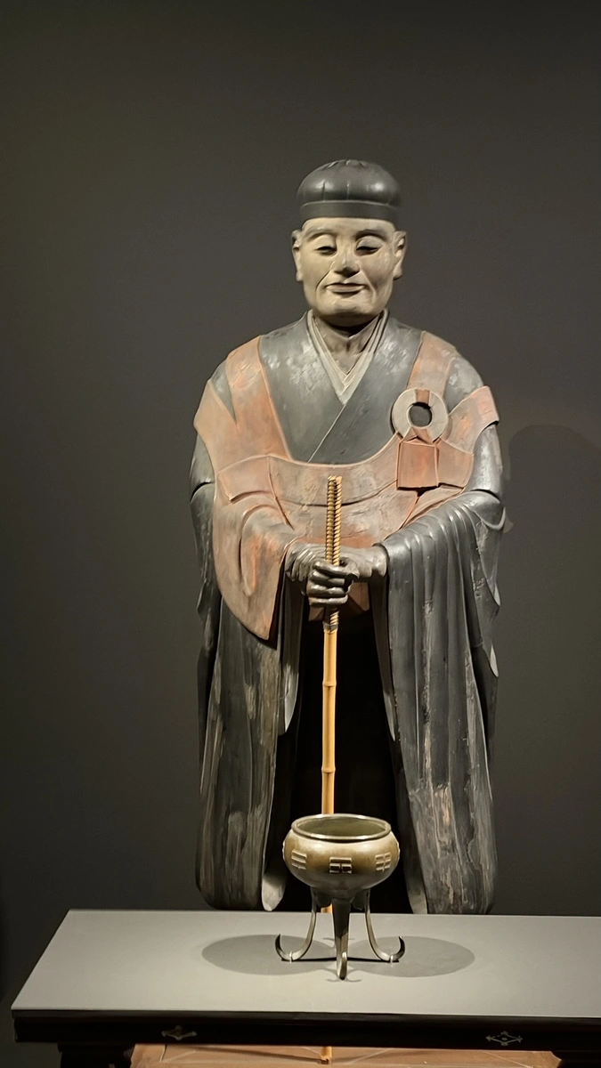 A frontal vertical photograph emphasizing Sen no Rikyu’s face, robes and hands on the staff