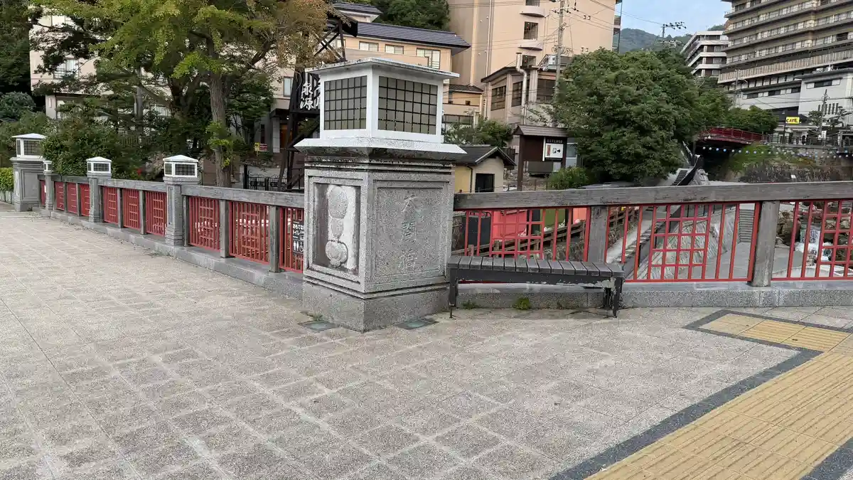 The railing of Taiko Bridge: a stone pillar and red railings looking down on the Arima River.