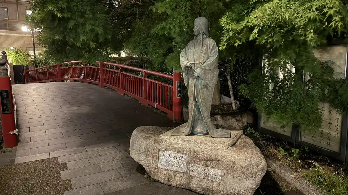 The Nene statue and Nene Bridge at night: the statue beside the red bridge.