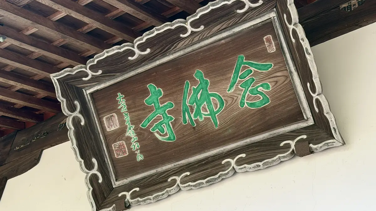 Nenbutsuji's plaque, with green lettering, hanging under the eaves.