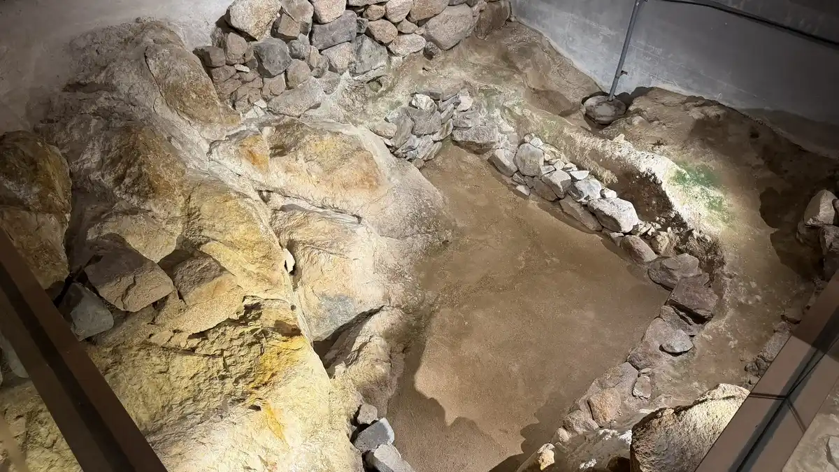 The rock-bath remains: rocks and stonework on the excavated surface, with a hollow like a bath.
