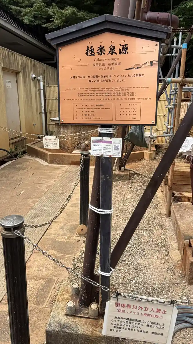 Information sign for Gokuraku Spring, in front of the fence.