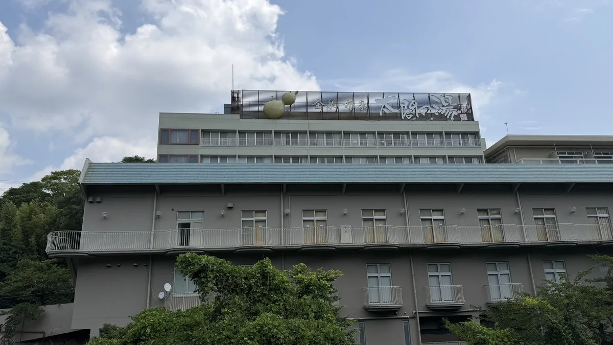 The outside of Taiko no Yu, a large building seen through trees from the side opposite the entrance.
