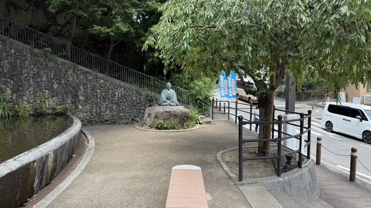 Yukemuri Square by day: the Hideyoshi statue at the end of a walkway beside the water.